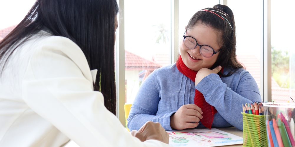 A child sitting at a table with an adult.