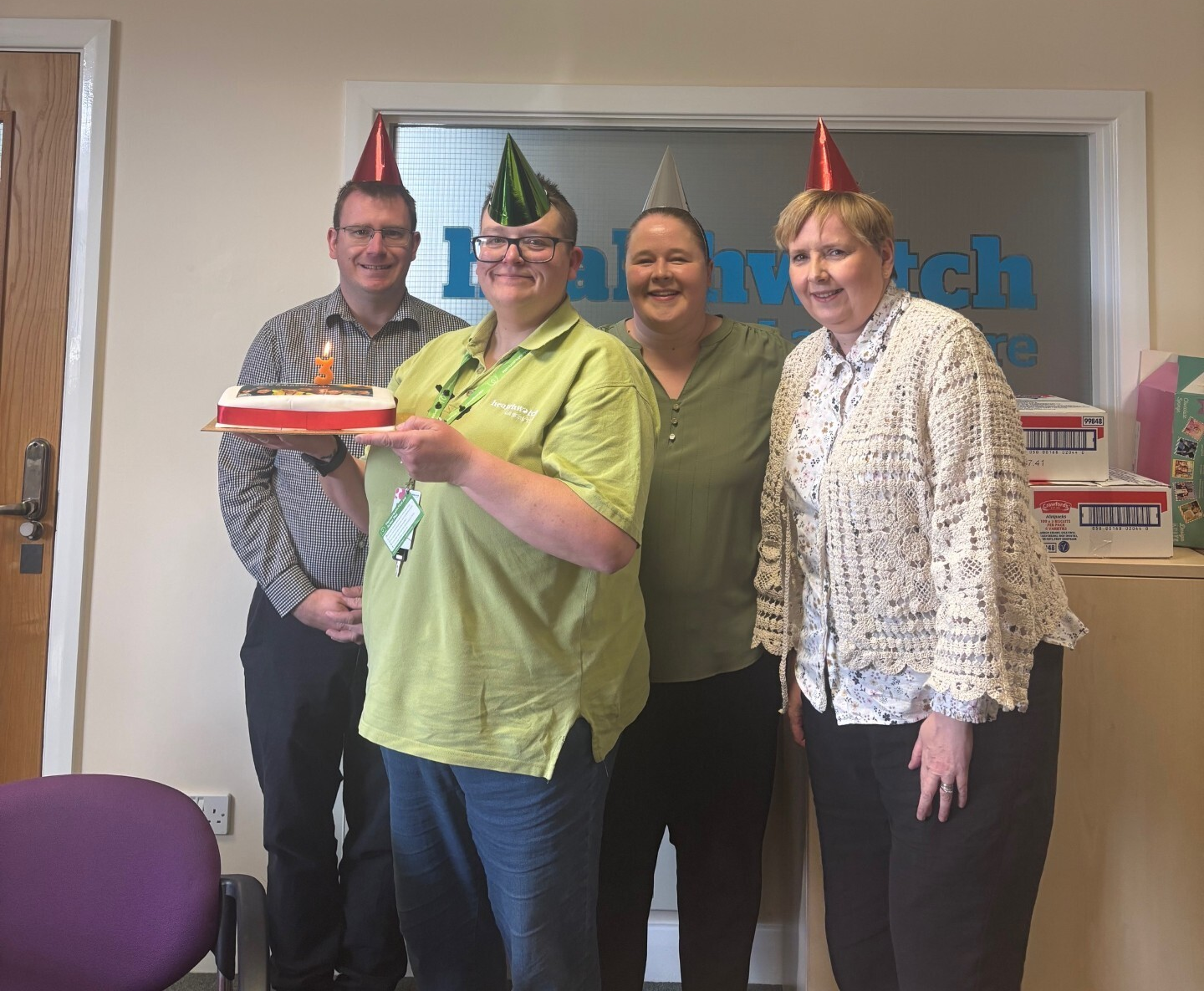 Image of Emmy, Dawn, Steve and Louise with a cake celebrating their work anniversary